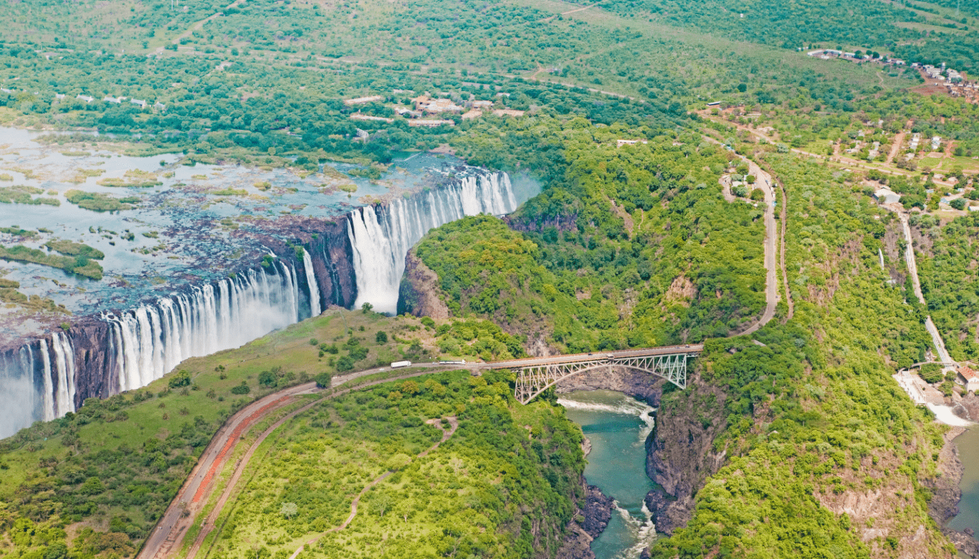 Gallery Slider -  Aerial View of Victoria Falls, Surrounding Greenery and Bridge Sustainable Safaris Africa - Destinations - Victoria Falls - Aerial View of Victoria Falls, Surrounding Greenery and Bridge