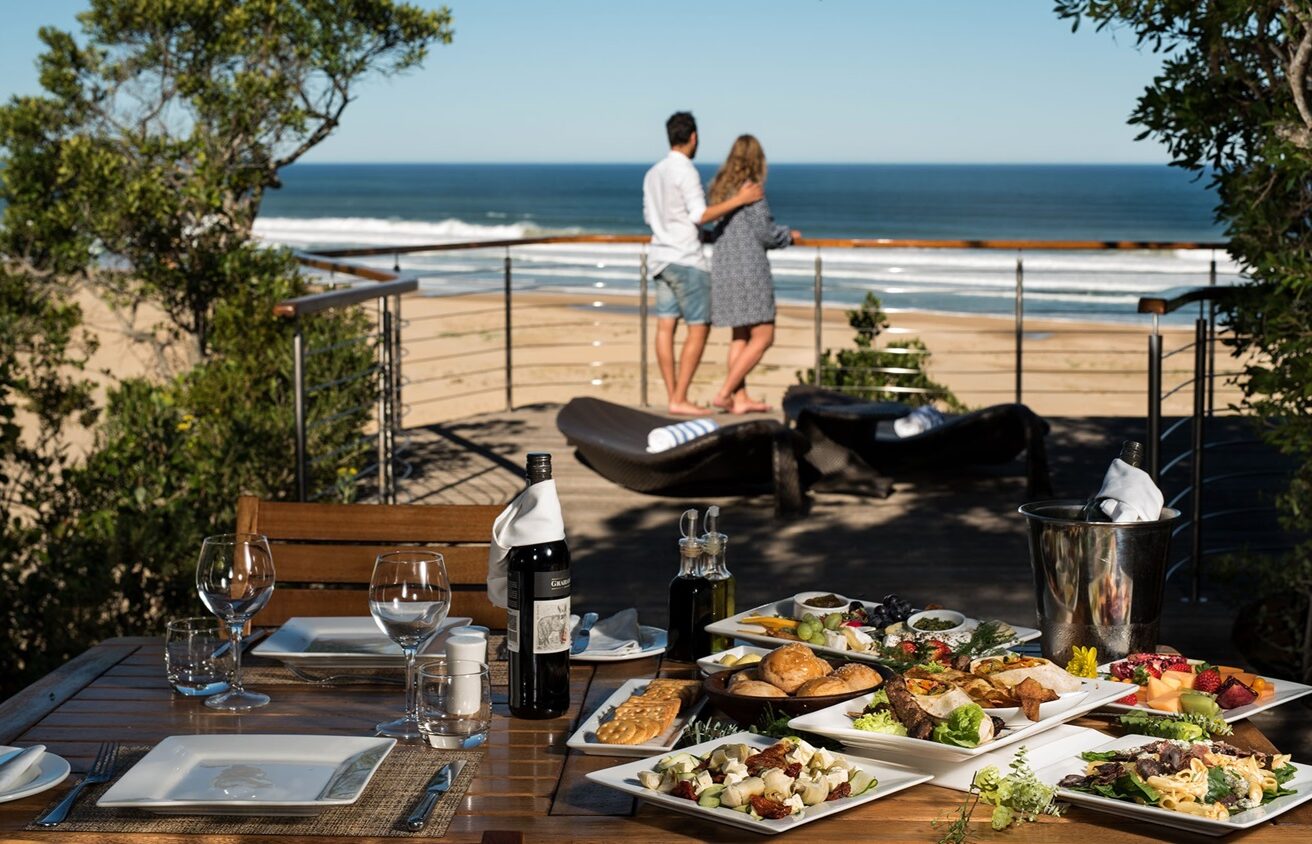 S008 - IT2 - Couple on the Balcony and Prepared Lunch on a Table Sustainable Safaris Africa - Journeys - Luxury Eastern Cape Couples Safari - Couple on the Balcony and Prepared Lunch on a Table